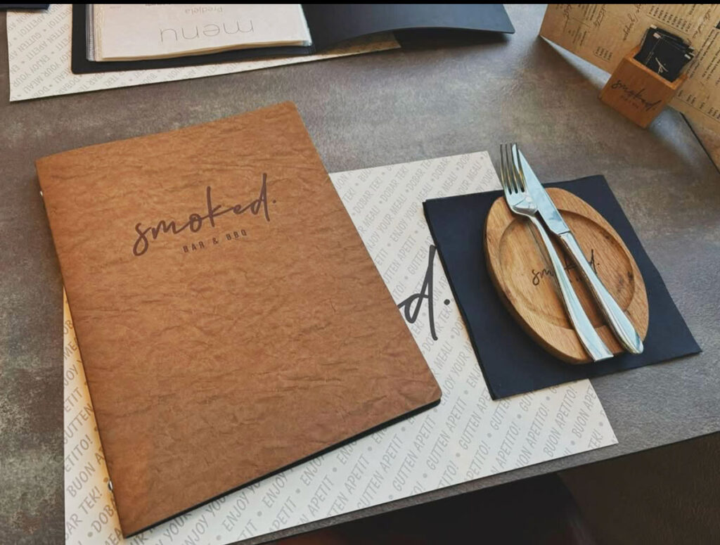 Luksuzne korice jelovnika i cjenika restorana Smoked Bar & BBQ na stolu s priborom